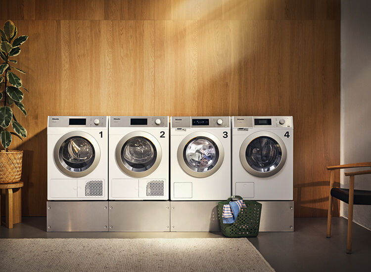 Vier genummerde wasautomaten op een sokkel in een gedeelde wasruimte